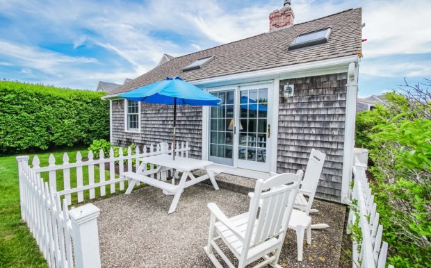 Photo of building exterior, and sliding doors to patio area with picnic table, and chairs.