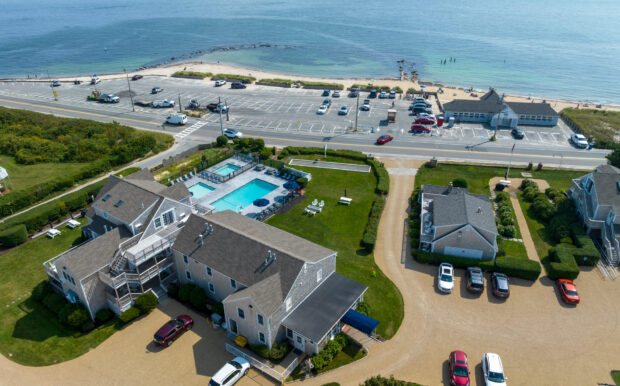 Aerial view of Beachside Village Resort showing the resort's swimming pool, parking lot, and beachfront location across the road.