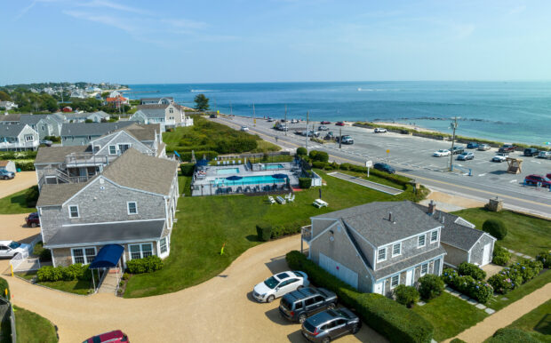 Aerial view of Beachside Village Resort with cottages, the pool area, and Cape Cod's ocean views in the background.