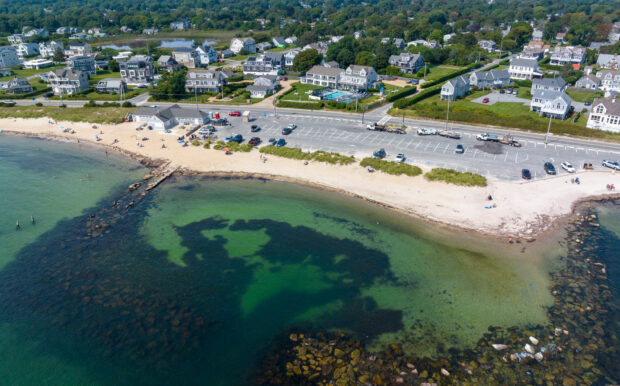 Aerial shot of Surf Drive Beach near Beachside Village Resort with calm waters, parking area, and sandy shore.