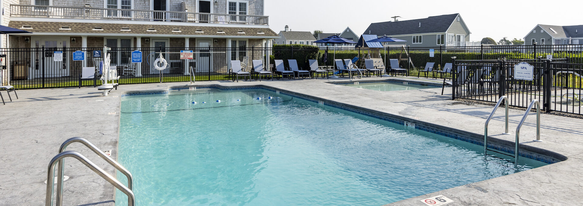 Close-up of the main pool at Beachside Village Resort surrounded by lounge chairs and blue umbrellas.